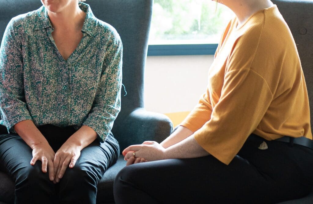 Two women talking, image cropped from neck down and focuses on hands.