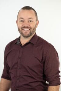 Portrait of a man in a maroon shirt smiling